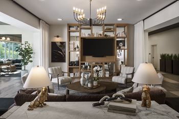 A living room with a large chandelier, a flat screen TV, and a bookshelf.